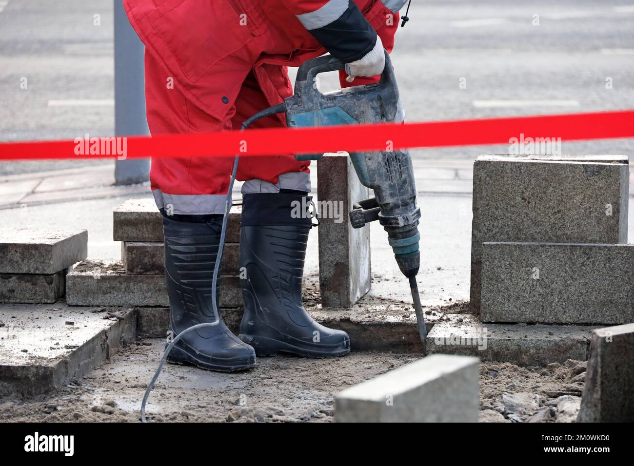 Worker repair the road surface with a jackhammer. Construction work, laying of paving slabs in city Stock Photo