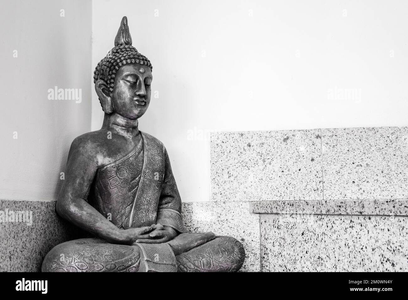 A gray metal figure of Buddha on some gray granite stairs Stock Photo