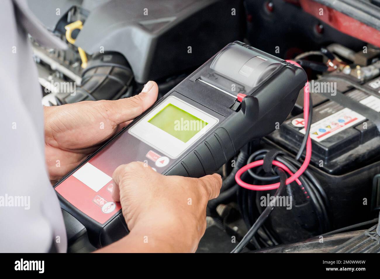 mechanic use voltmeter checking voltage of car battery in car service