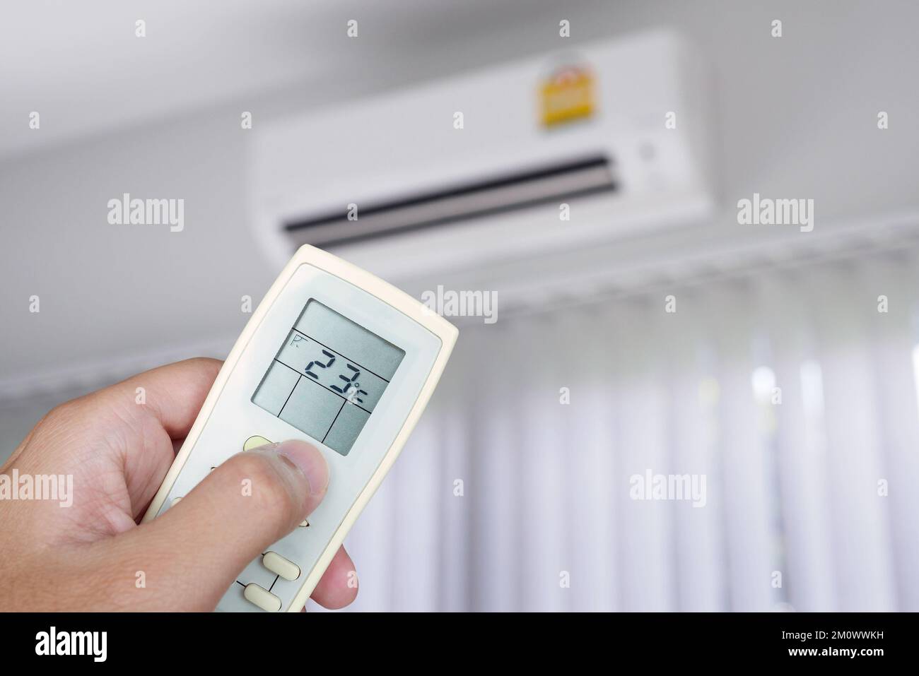 Hand using remote control with air conditioner in the room Stock Photo
