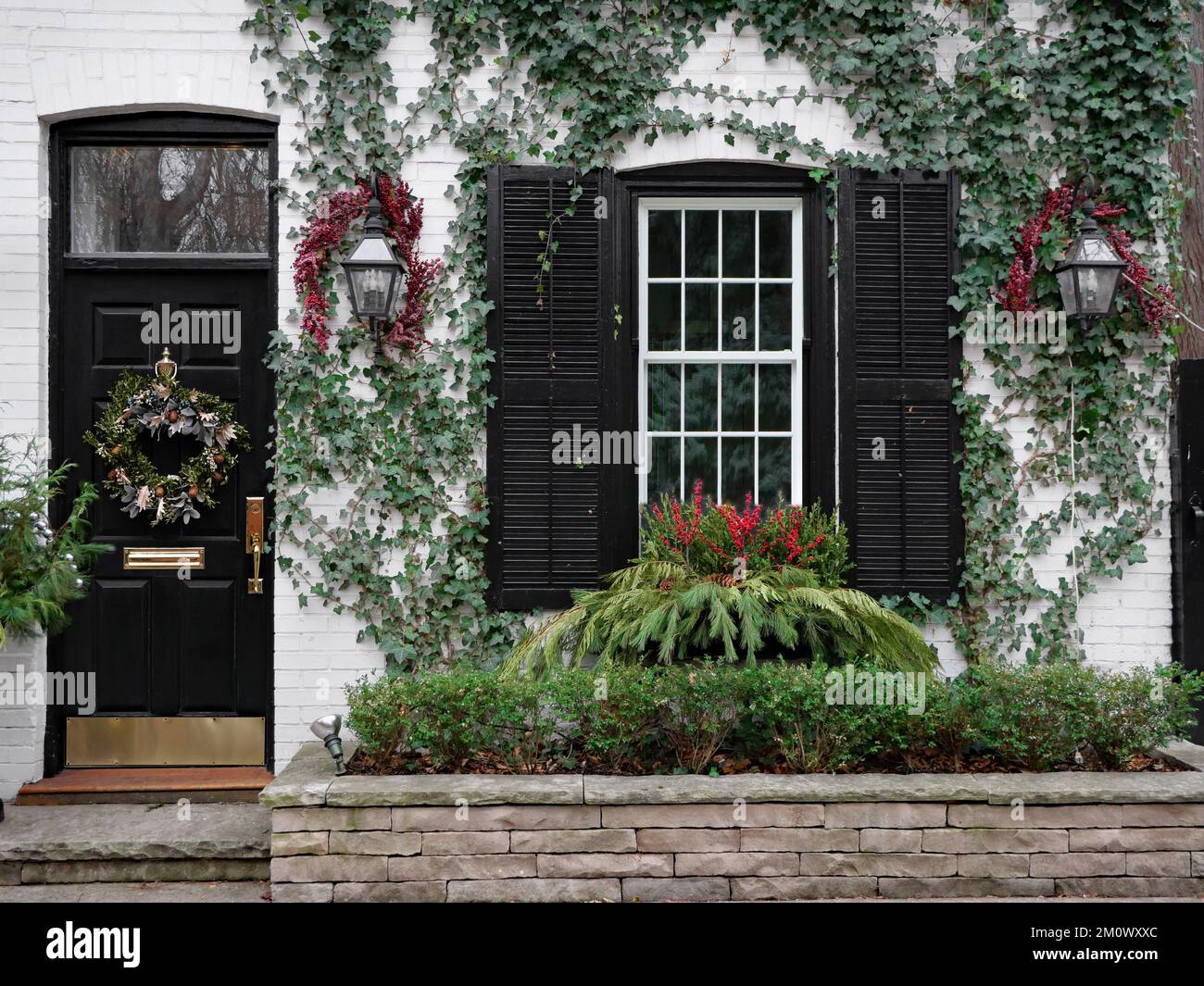 Front of old brick house with Christmas wreath on front door and holly berry decorations Stock Photo