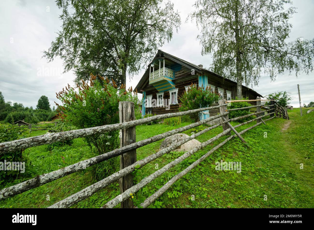 Wooden village house behind a fence of poles Stock Photo - Alamy