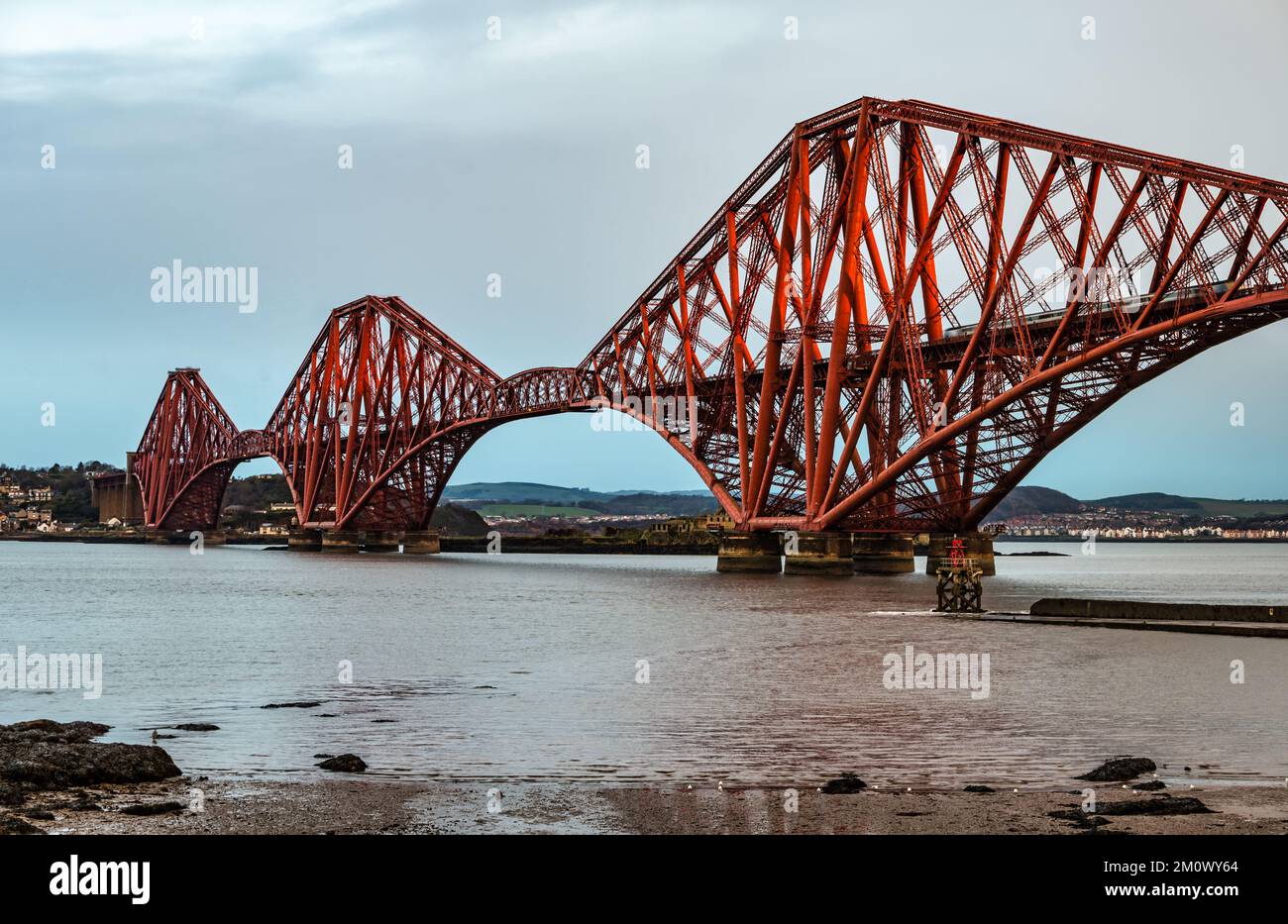 Iconic Forth Rail cantilever bridge in early morning light woth train crossing, Firth of Forth, Scotland, UK Stock Photo