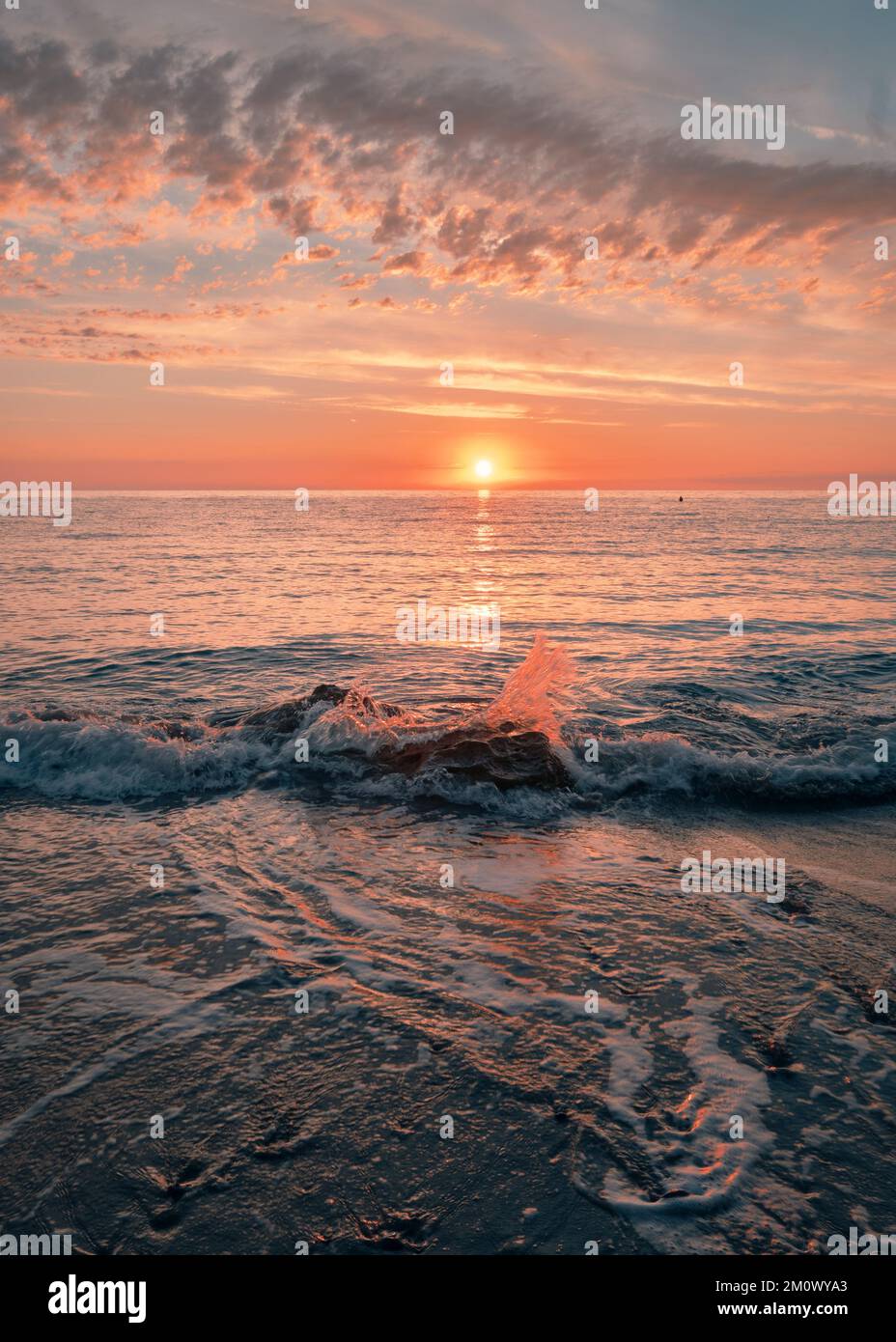 Sunrise on the seashore on the Italian Riviera. Splashing waves illuminated by sunlight. Vacation travel holiday banner, summer mood. The Ligurian Sea, Italy Stock Photo