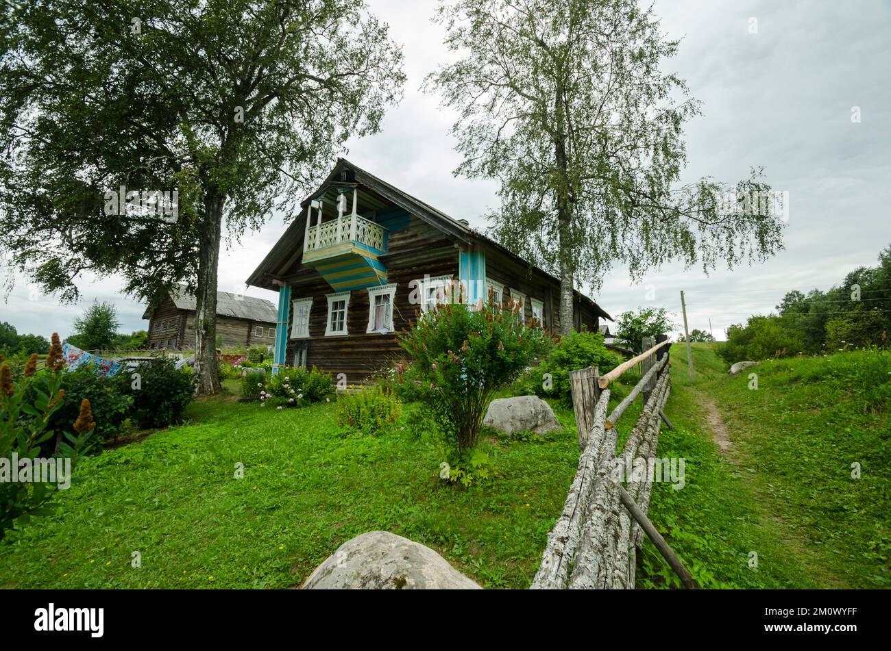 Wooden village house behind a fence of poles Stock Photo - Alamy