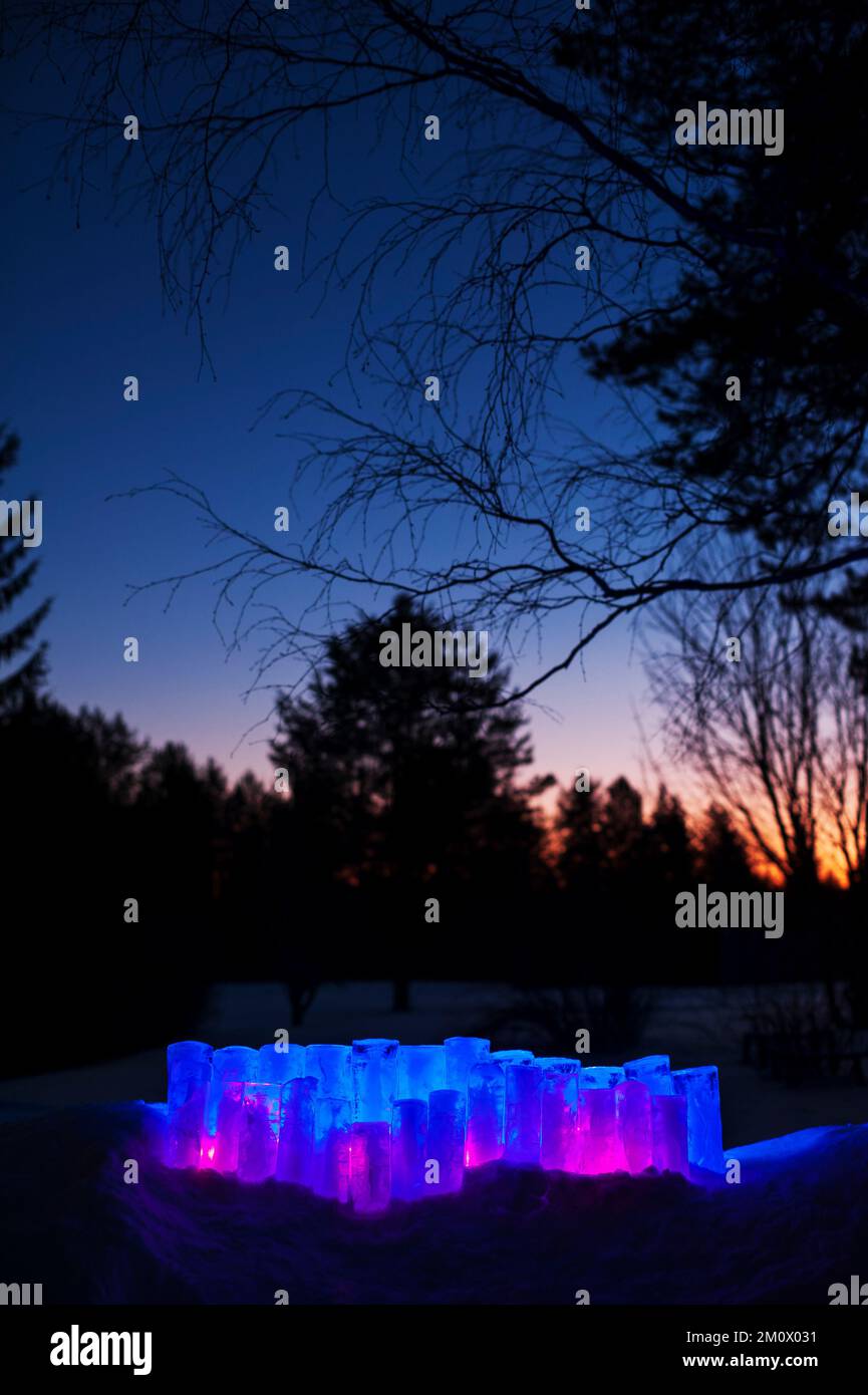 Ice lanterns with led lights in snow. Winter evening in the garden. Stock Photo