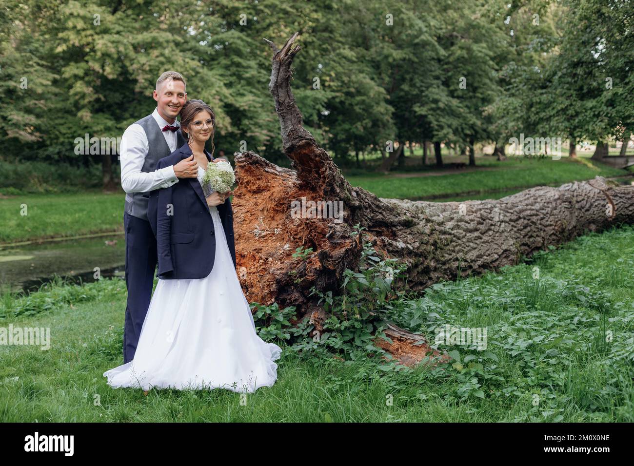 Portrait of wonderful wedding couple standing near roots of fallen tree ...