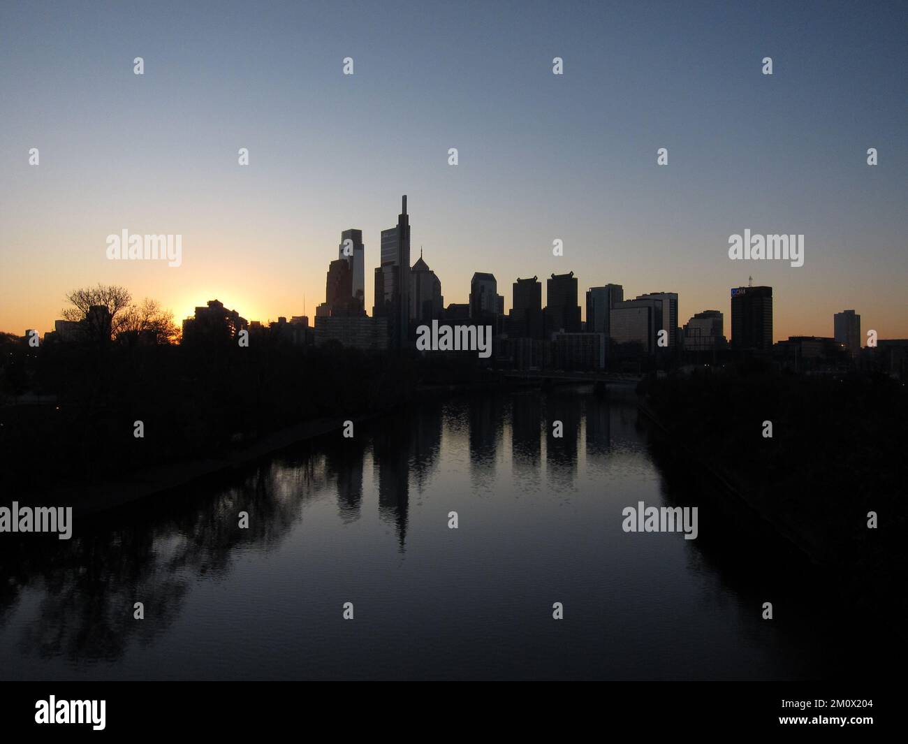 The Philadelphia skyline is seen silhouetted against the sunrise over the Schuylkill River. Stock Photo