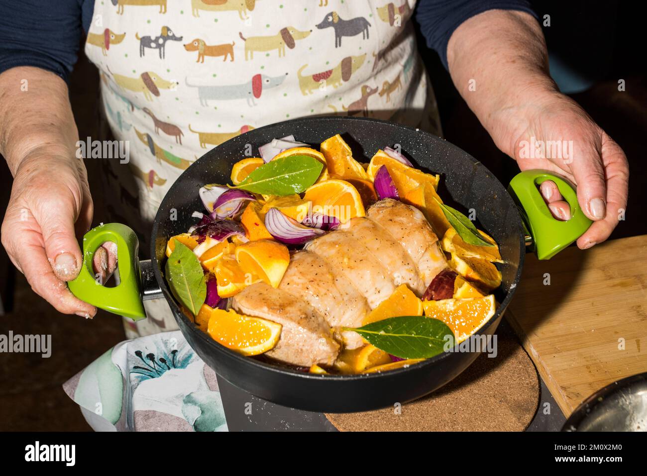 Woman holding pan with orange pork loin prepared to cook in the oven Stock Photo