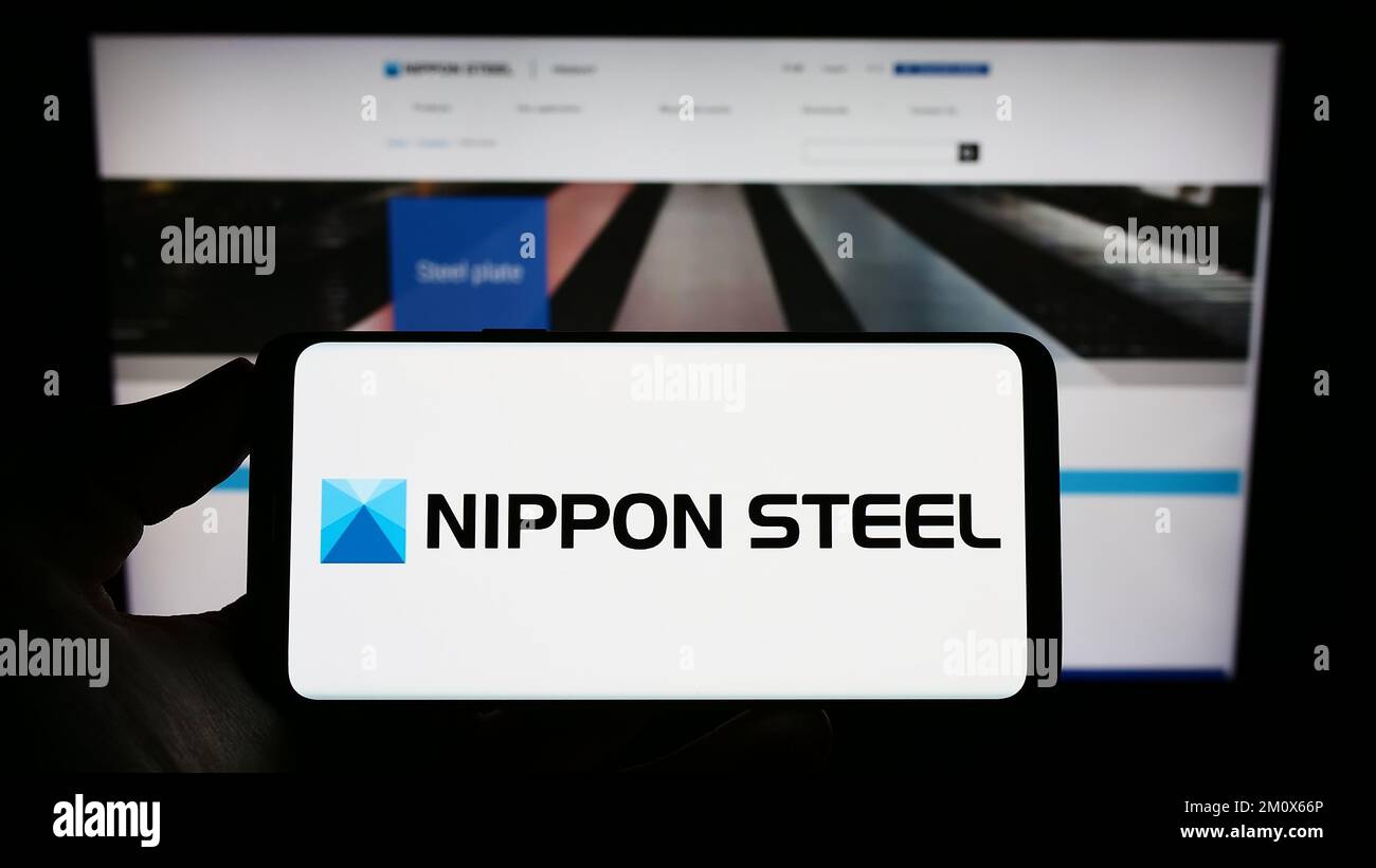 Person holding cellphone with logo of Japanese company Nippon Steel Corporation on screen in