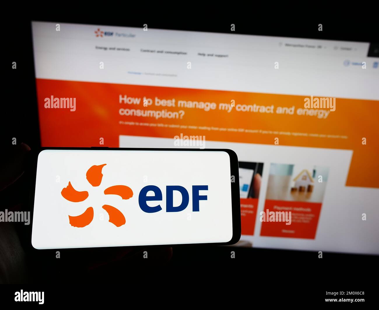 Person holding smartphone with logo of energy company Electricite de France S.A. (EDF) on screen in front of website. Focus on phone display. Stock Photo