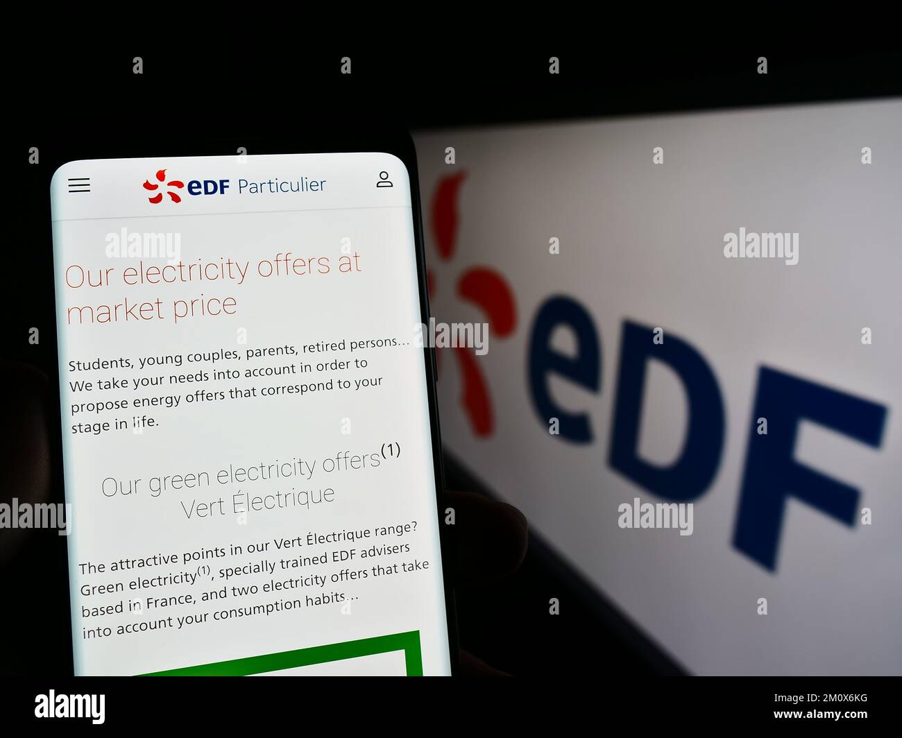 Person holding cellphone with webpage of energy company Electricite de France S.A. (EDF) on screen with logo. Focus on center of phone display. Stock Photo