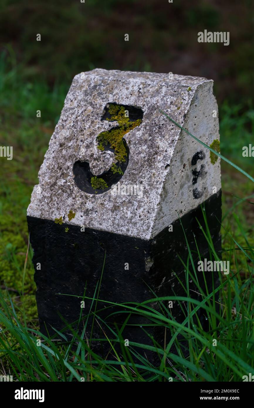 A black and white stone sign with the number three by the road Stock Photo