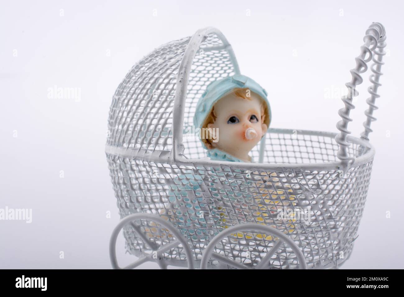 Little baby doll in baby carriage on a white background Stock Photo