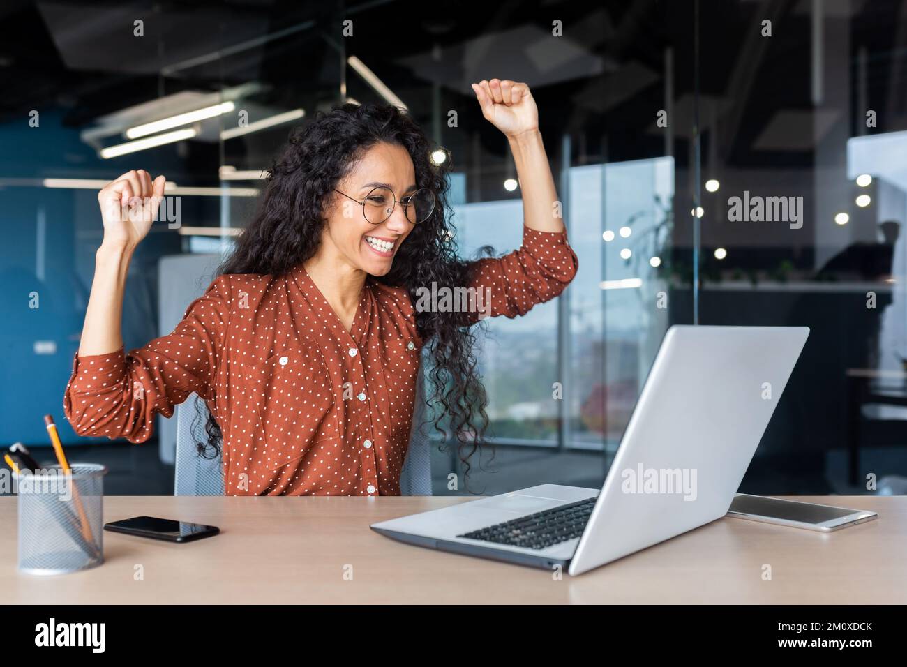 A beautiful young Latin American woman freelancer sits in the office at ...