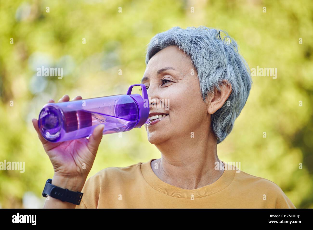 Close up image attractive mature woman holds plastic reusable bottle make sip drinking still mineral water during morning work out or stroll in summer Stock Photo