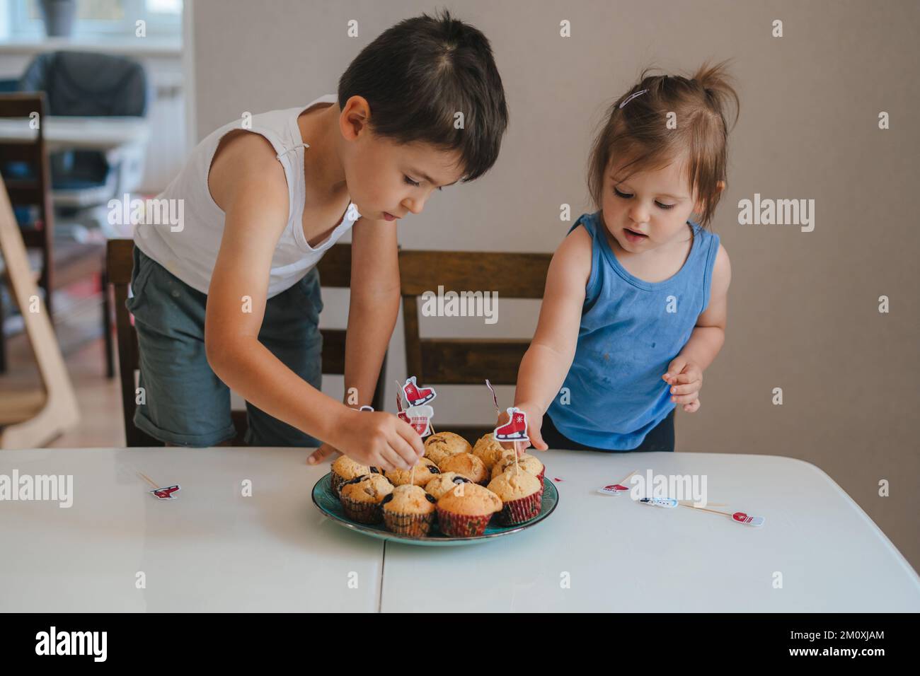 Two children putting decorations on home-baked cakes. Happy birthday. Stock Photo