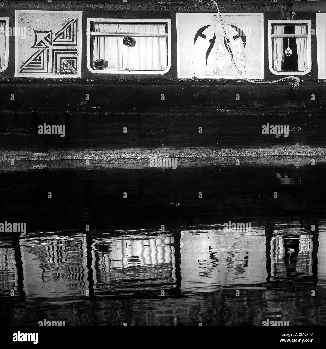 Black and white photograph close up of Narrowboat on British Waterways canalside, showing a Sepia toned infrared image of boat art signage Stock Photo