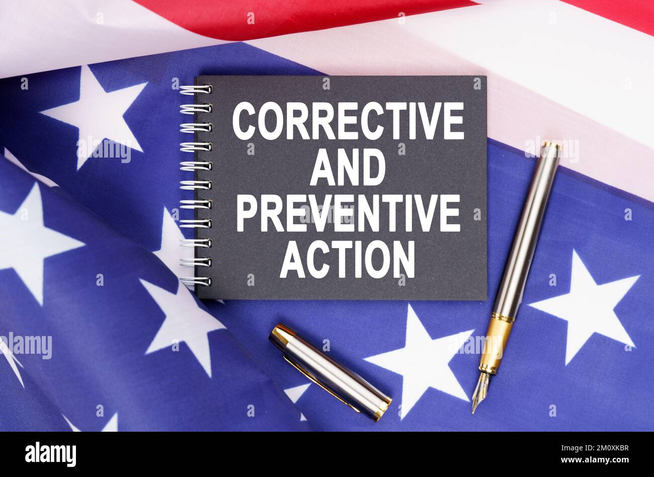 Business and finance concept. On the table is an American flag, a pen and a notebook with the inscription - CORRECTIVE AND PREVENTIVE ACTION Stock Photo