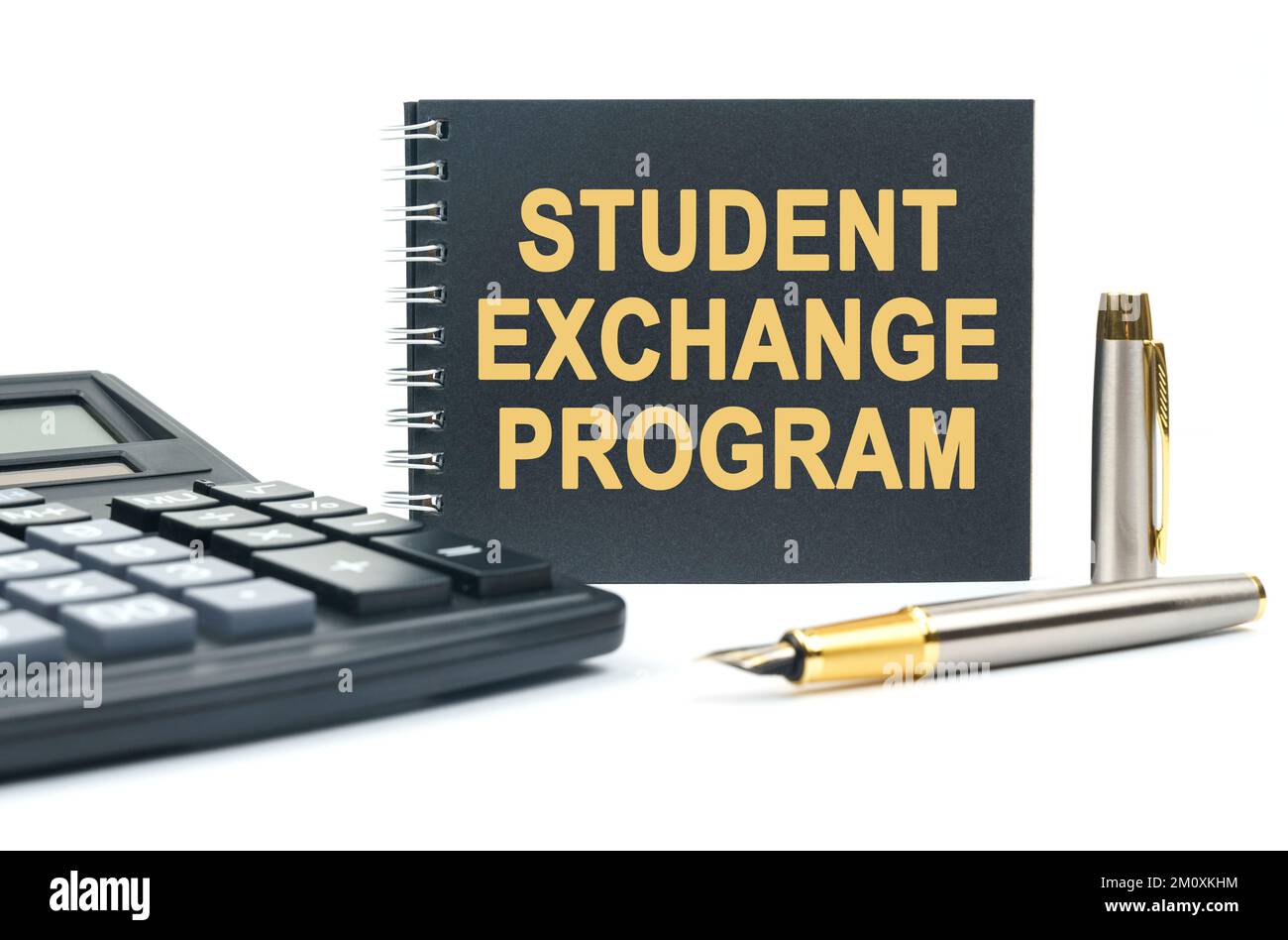 Business and finance. On a white background, there is a calculator, a pen and a black notebook with the inscription - STUDENT EXCHANGE PROGRAM Stock Photo