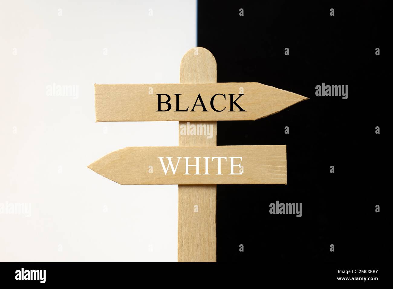 Cartel de madera señalando negro hacia un lado y blanco hacia el otro Stock Photo