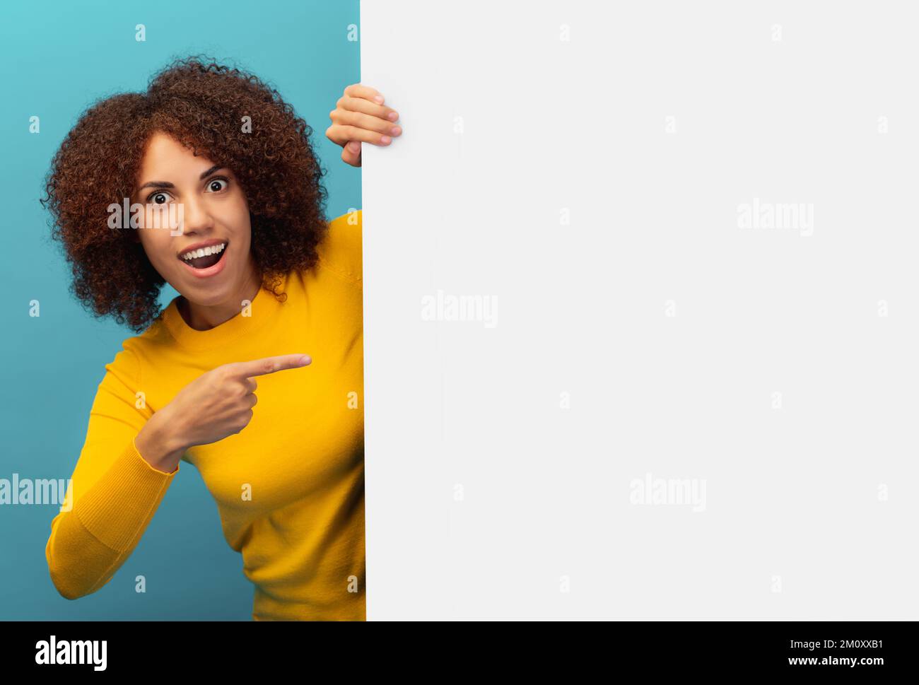 Discount black friday or sale african american woman peeking out from empty white board and pointing her finger Stock Photo
