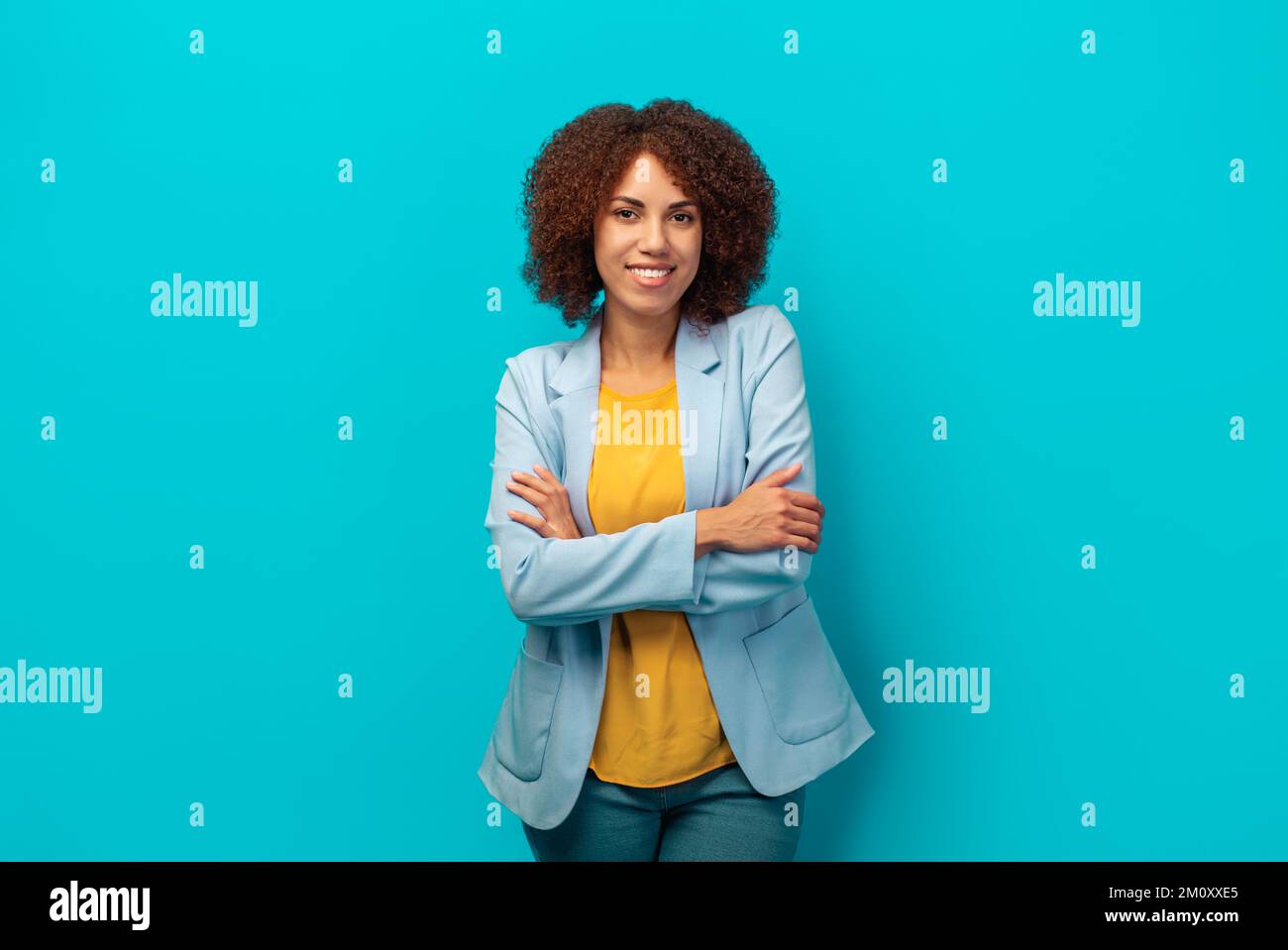 Hiring, career concept smiling successful African American woman with curly hair in jacket on blue background Stock Photo