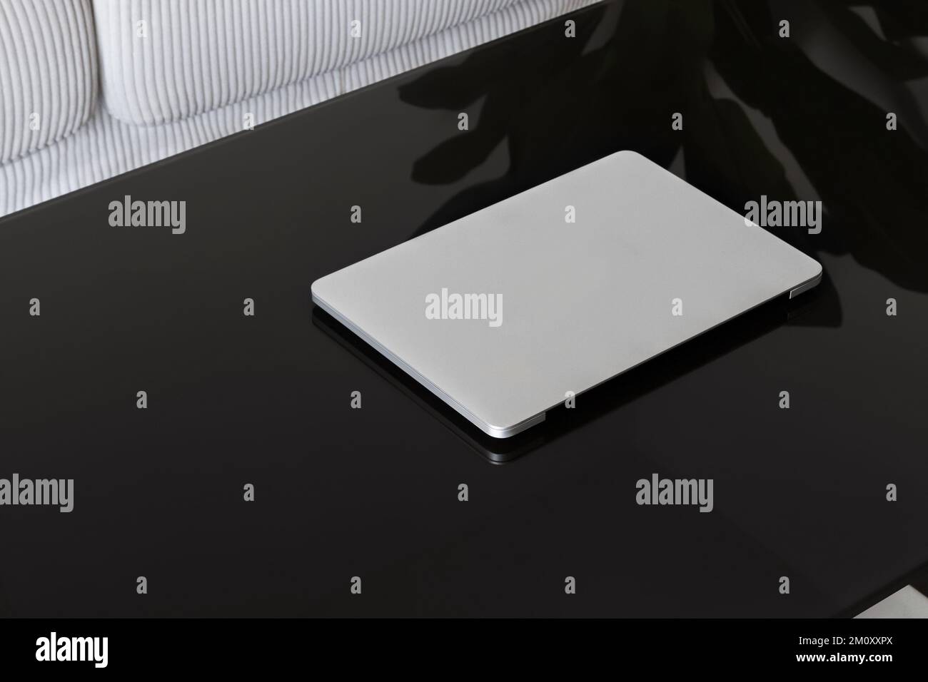 Laptop Closed. Laptop on a black glass table against a white sofa Stock ...