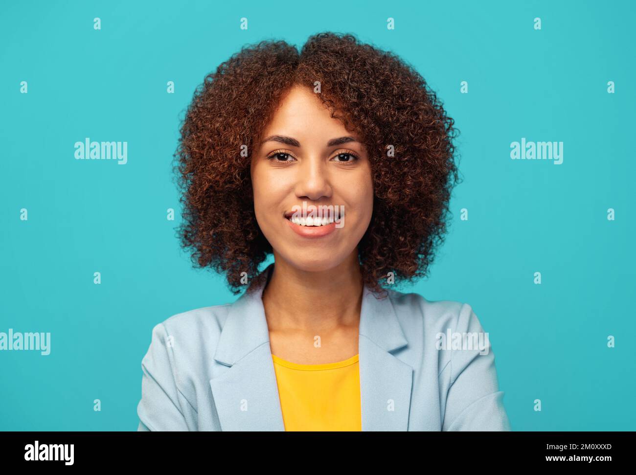 Hiring, career concept smiling successful African American woman with curly hair in jacket on blue background Stock Photo