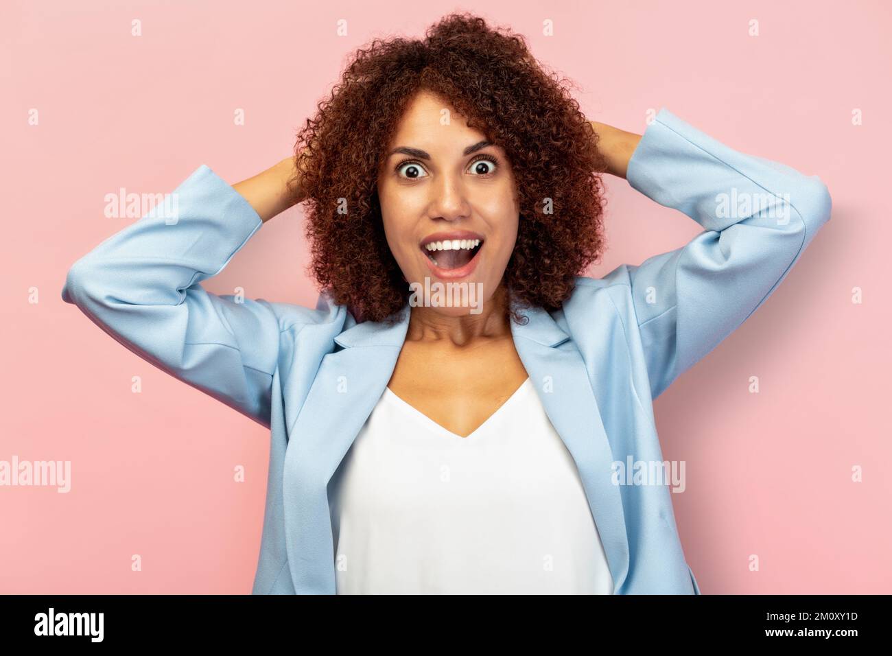 Excited woman overjoyed with new position or job Happy female with curly hair holding her head and screaming  Stock Photo