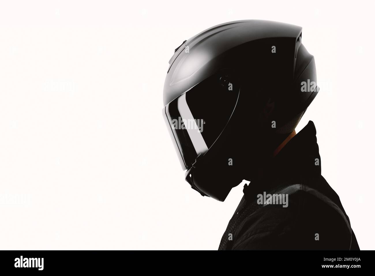 Portrait of a motorcycle rider posing with a black helmet on a white background. Stock Photo