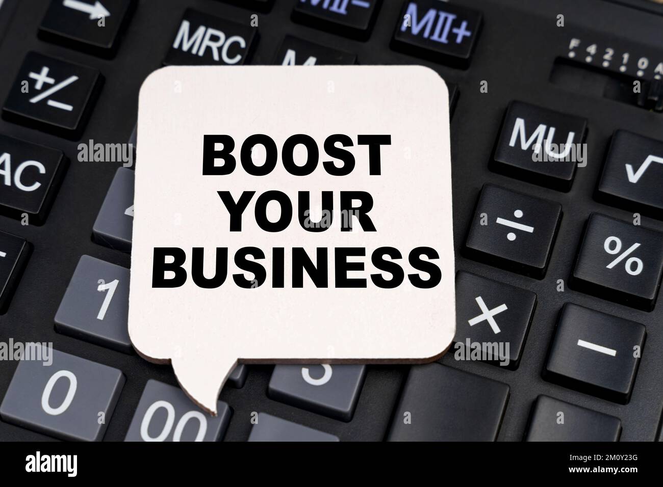 Business and economy concept. There is a white plate on the calculator with the inscription - BOOST YOUR BUSINESS Stock Photo
