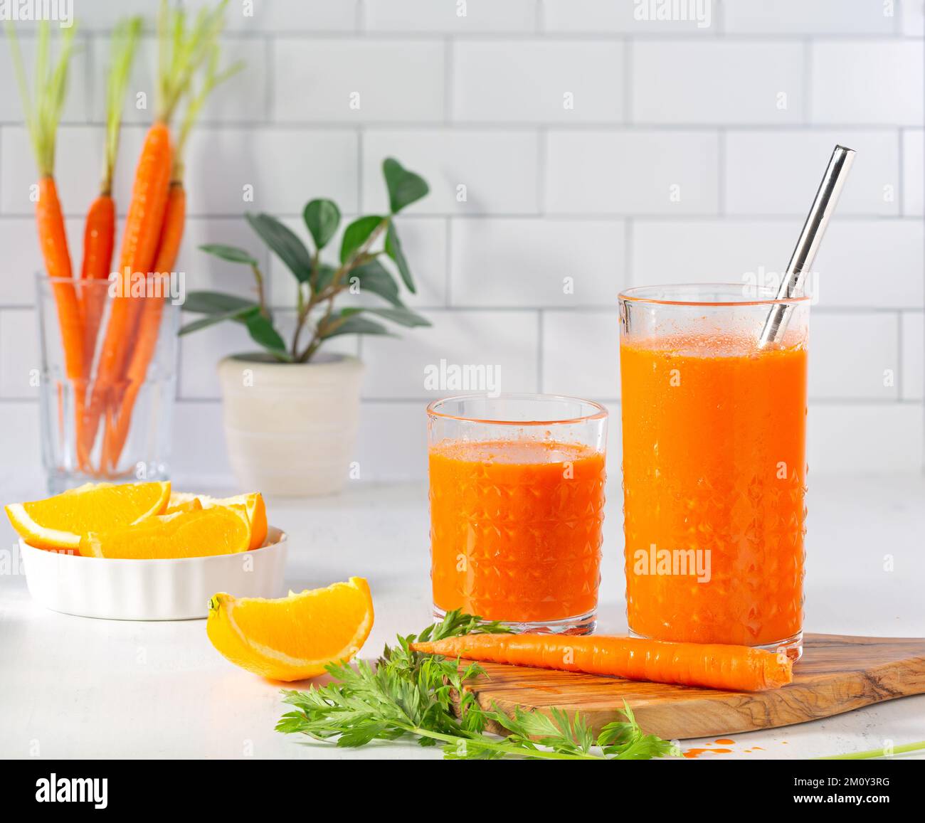 Two healthy and delicious glasses of carrot juice in a light and bright kitchen counter scene with copy space Stock Photo