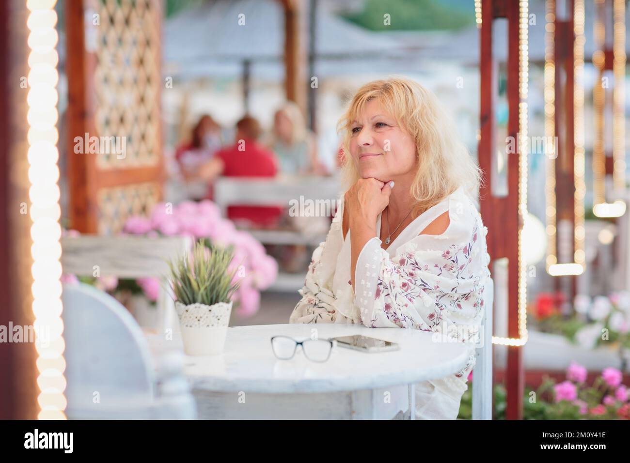 Portrait of woman sitting on the terrace of a beach cafe Stock Photo ...