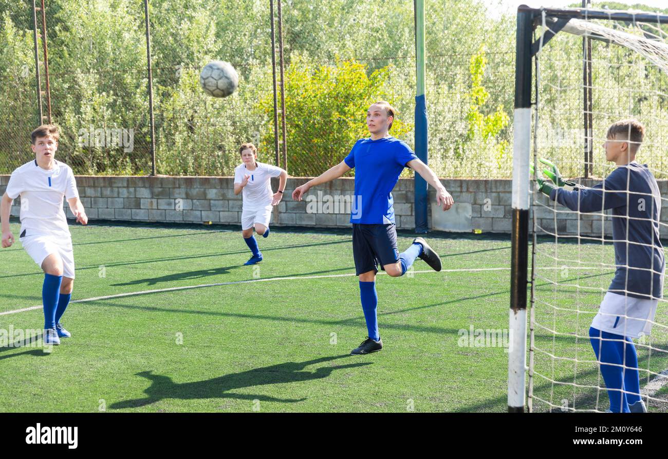 Game of football match between two teams of teenagers in white and blue
