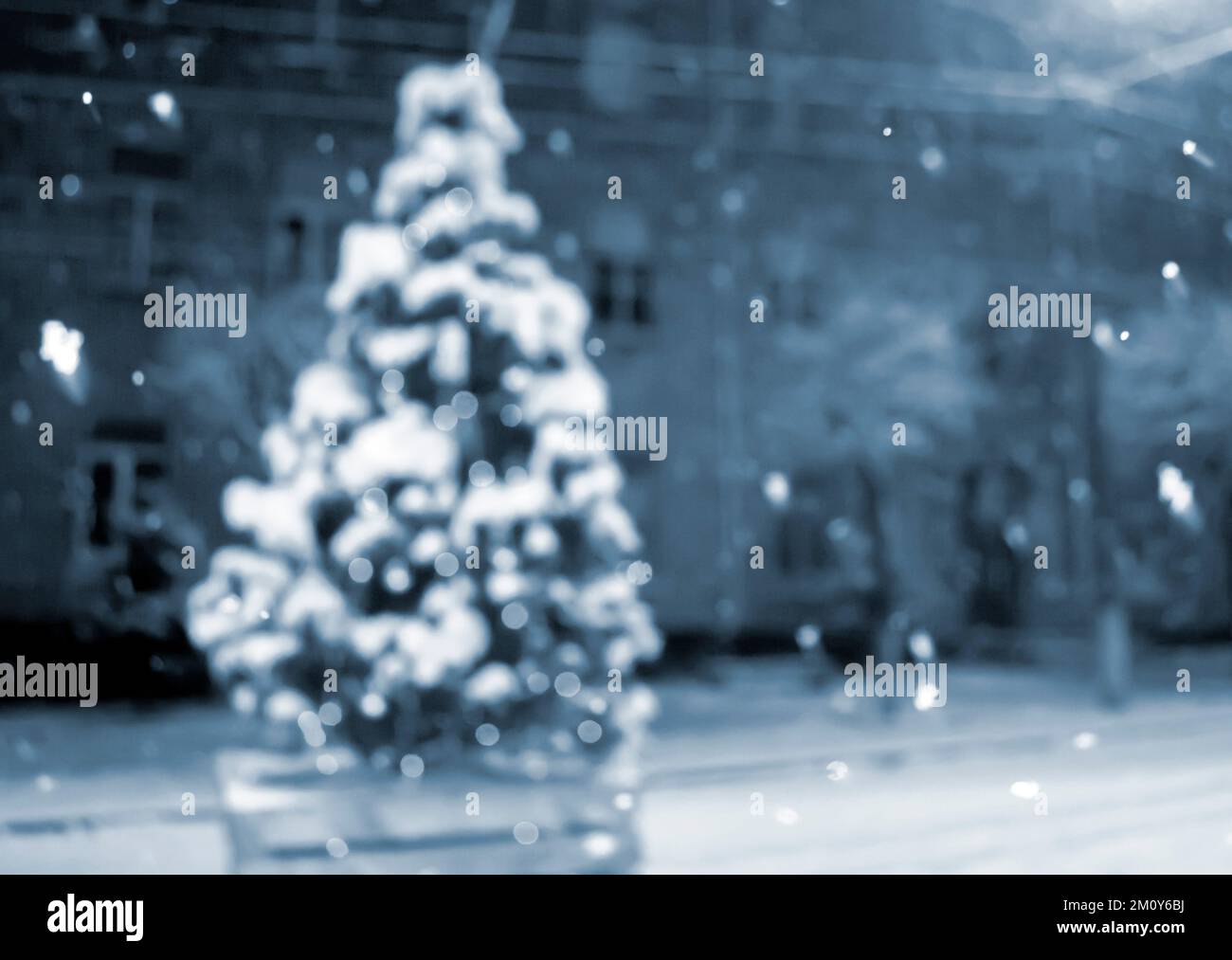 Christmas tree covered snow, glowing colorful lights during snowfall outdoors. Abstract Christmas New Year background. Blurred snowy winter background. Light twinkling. Blue color Stock Photo