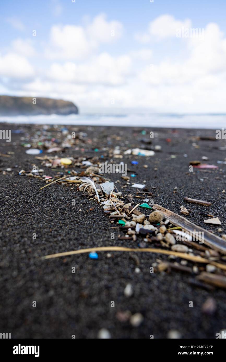 Trash in the sand, plastic waste by the ocean, sad and unsustainable