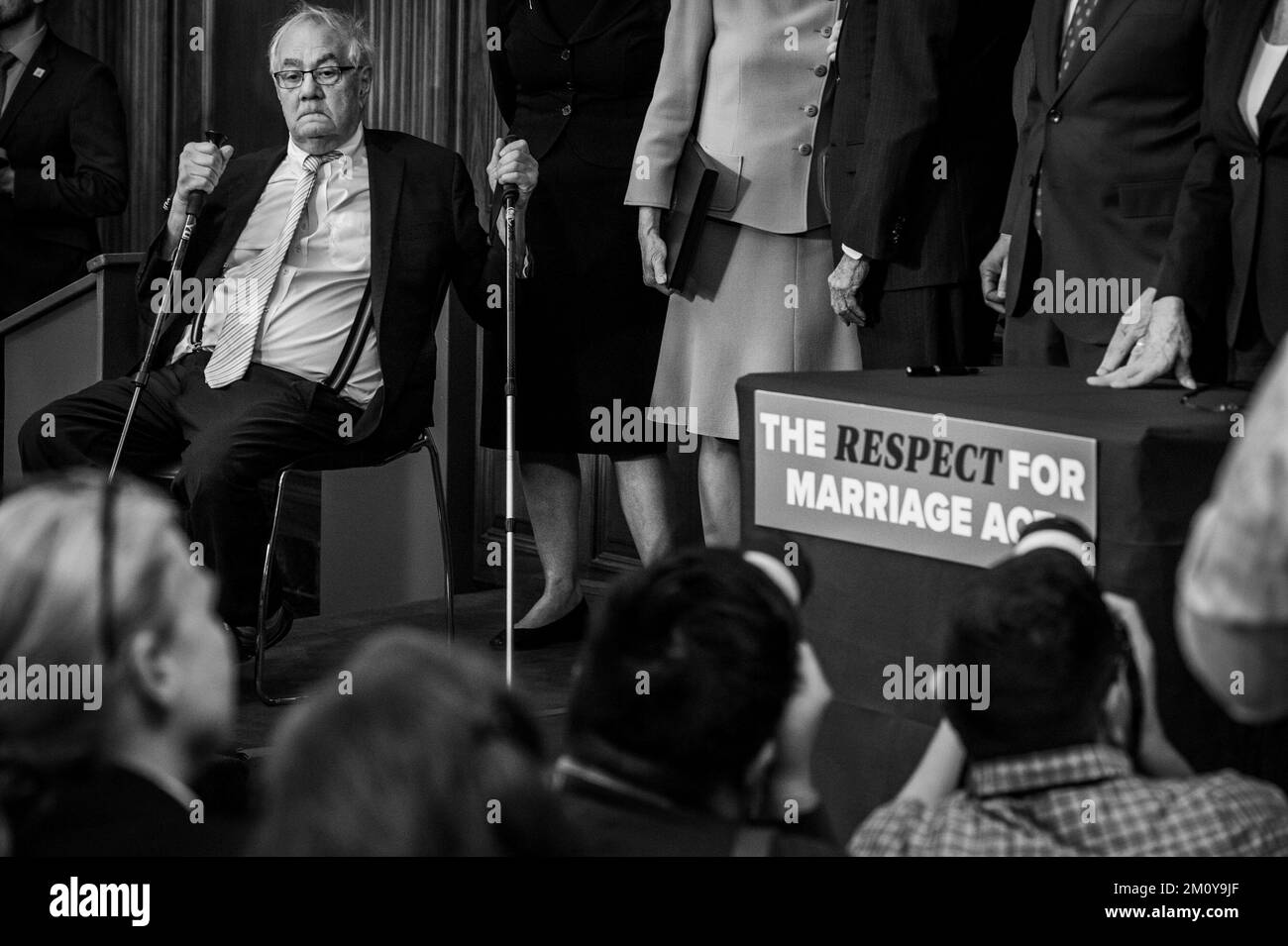 Washington, DC, US December 8, 2022. Former United States Representative Barney Frank (Democrat of Massachusetts) sits to himself son stage while Speaker of the United States House of Representatives Nancy Pelosi (Democrat of California), United States Senate Majority Leader Chuck Schumer (Democrat of New York) and bipartisan Senate and House members pass around the newly signed bill H.R.8404, the âRespect for Marriage Actâ during a bill enrollment ceremony at the US Capitol in Washington, DC, Thursday, December 8, 2022. Out of all the people on stage passing the bill around to touch, Mr. Stock Photo