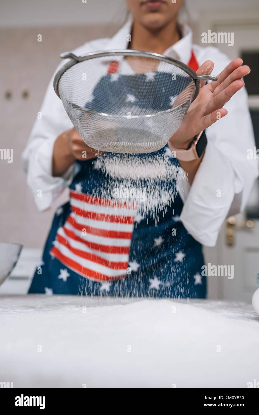 Woman sifting flour through sieve. Selective focus. Stock Photo