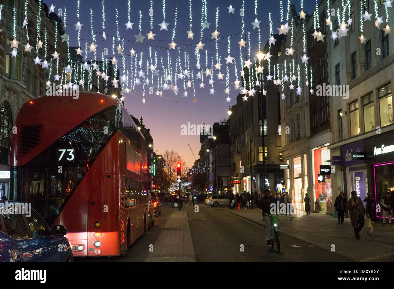 London, UK, 8 December 2022: Christmas lights add sparkle to the sunset sky at dusk on Oxford Street in the West End. Shoppers crowd the streets despite concerns about consumer confidence during the cost of living crisis. Anna Watson/Alamy Live News Stock Photo