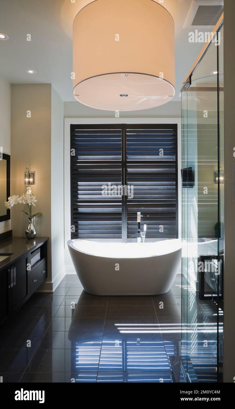 Large white round shaped lighting fixture over freestanding bathtub in