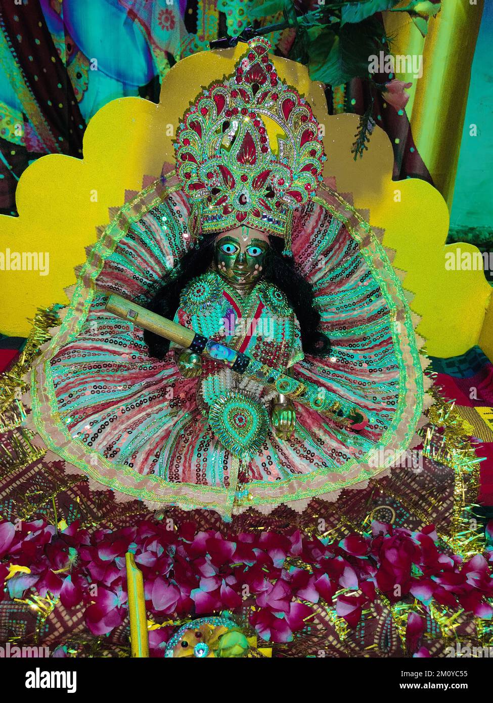 A closeup shot of the idol of Laddu Gopal, sitting in a colorful dress, holding a flute Stock Photo