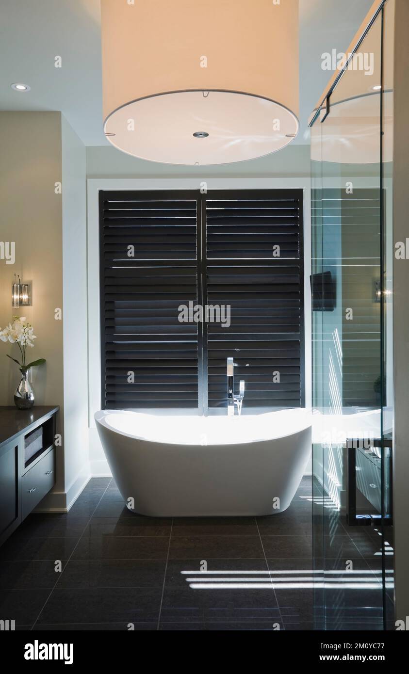 Large white round shaped lighting fixture over freestanding bathtub in