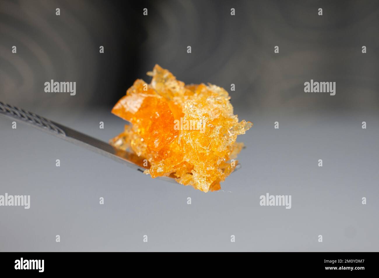 amber yellow cannabis wax concentrate dripping from the dabbing tool closeup. Stock Photo