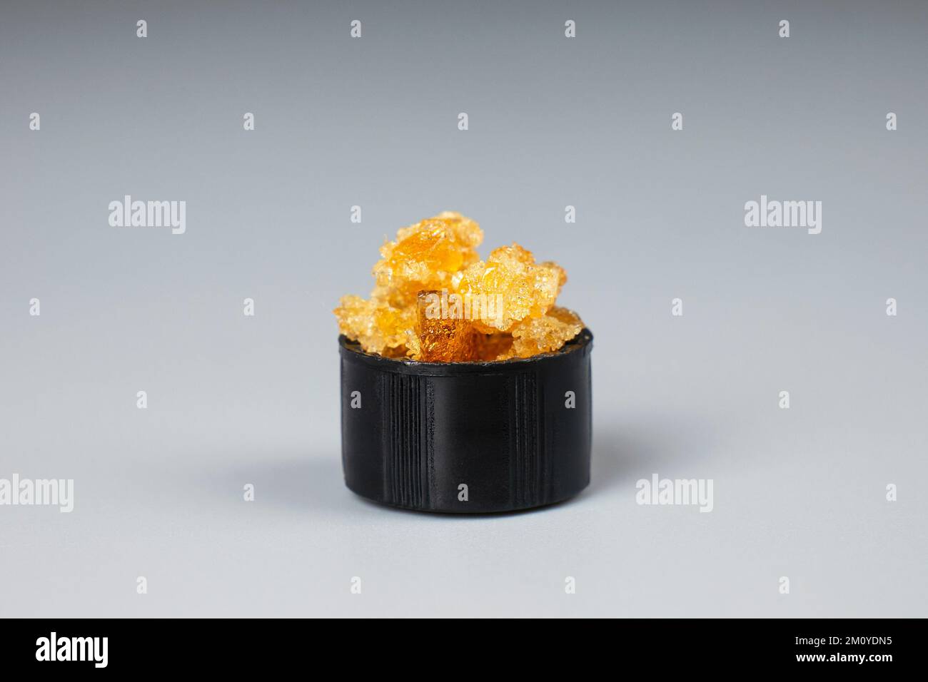 golden crystals of cannabis wax, glass container with crumbs of marijuana concentrate and copy