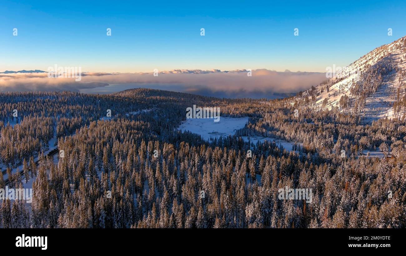 Aerial view of sunrise in the snow covered mountains with Lake Tahoe in the distant background. Stock Photo