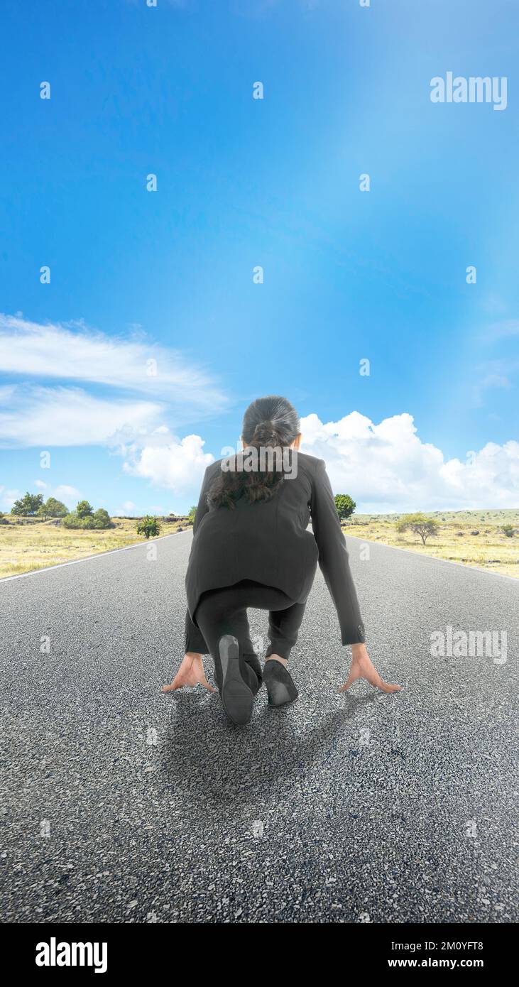 Rear view of Asian businesswoman in start position ready to run on the ...