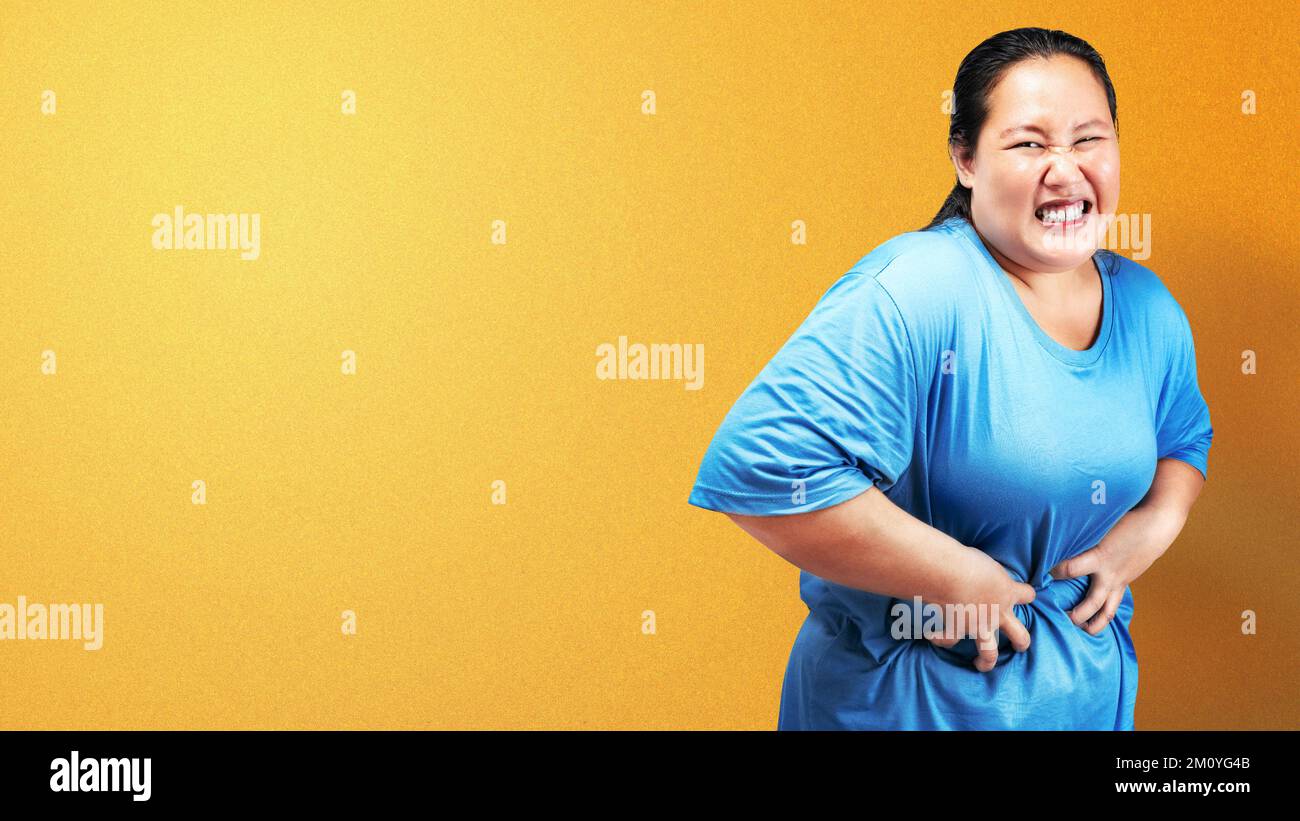 Asian fat overweight woman feeling stomach ache with colored background