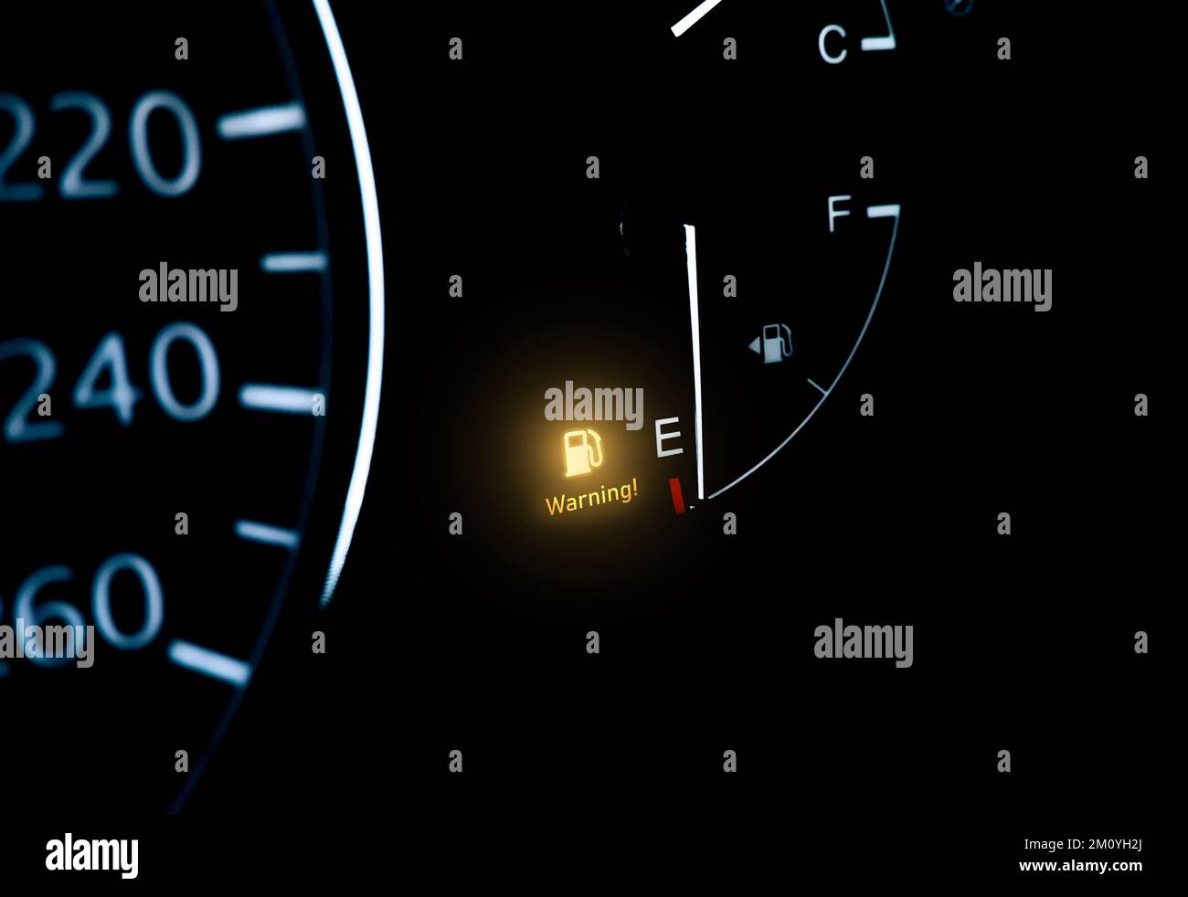 Low fuel indicator light on car dashboard with copy space below on black background Stock Photo