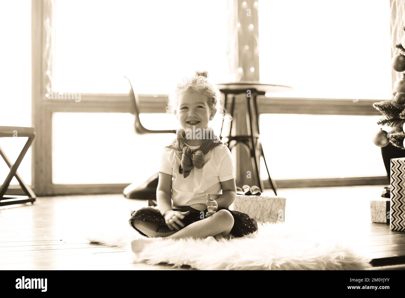 happy little girl sitting on the carpet in the living room. black and ...